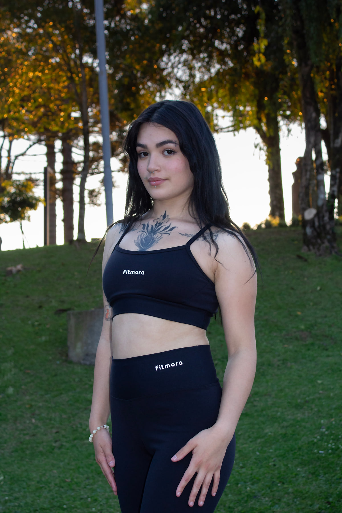 Modelo com top e legging da Coleção Black Fitmora em um parque ao entardecer