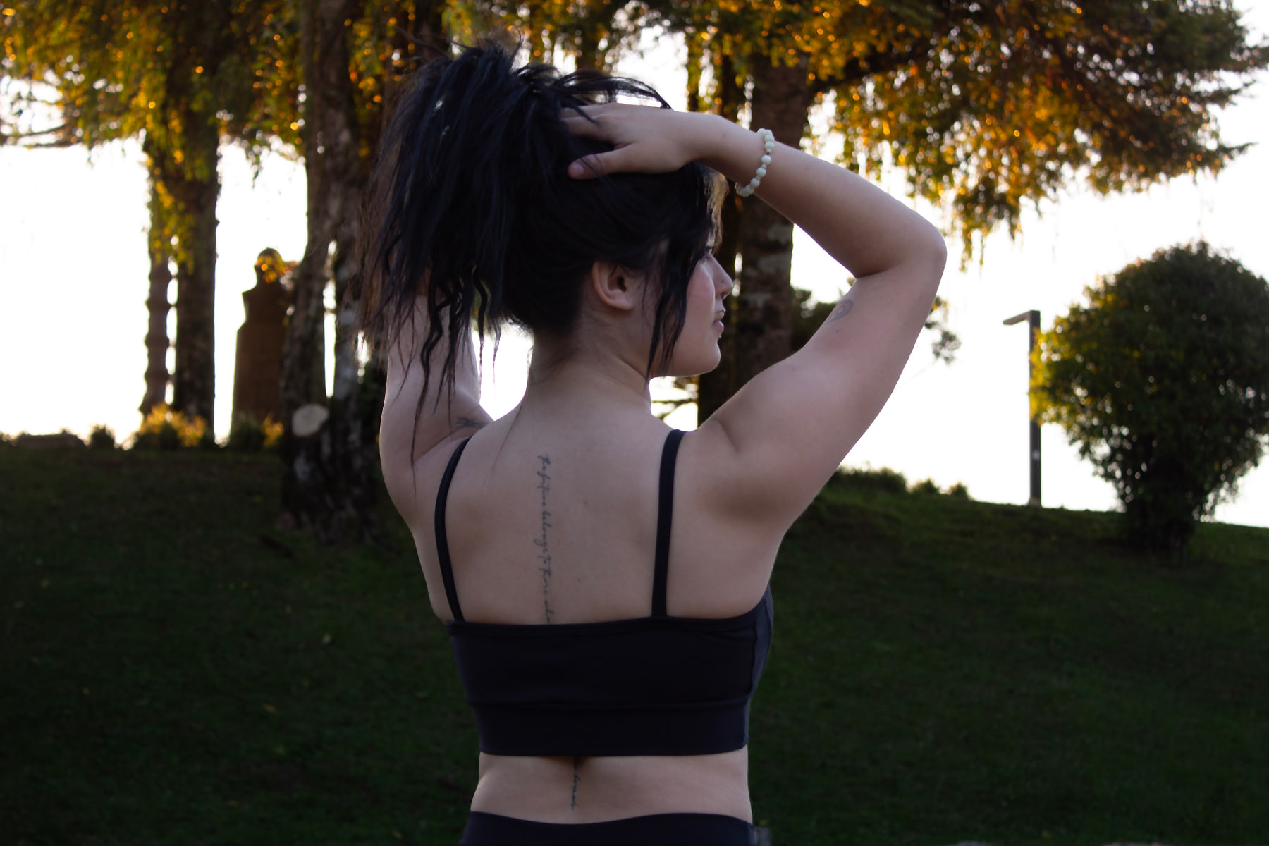 Modelo prendendo o cabelo, vista das costas do top Black Fitmora